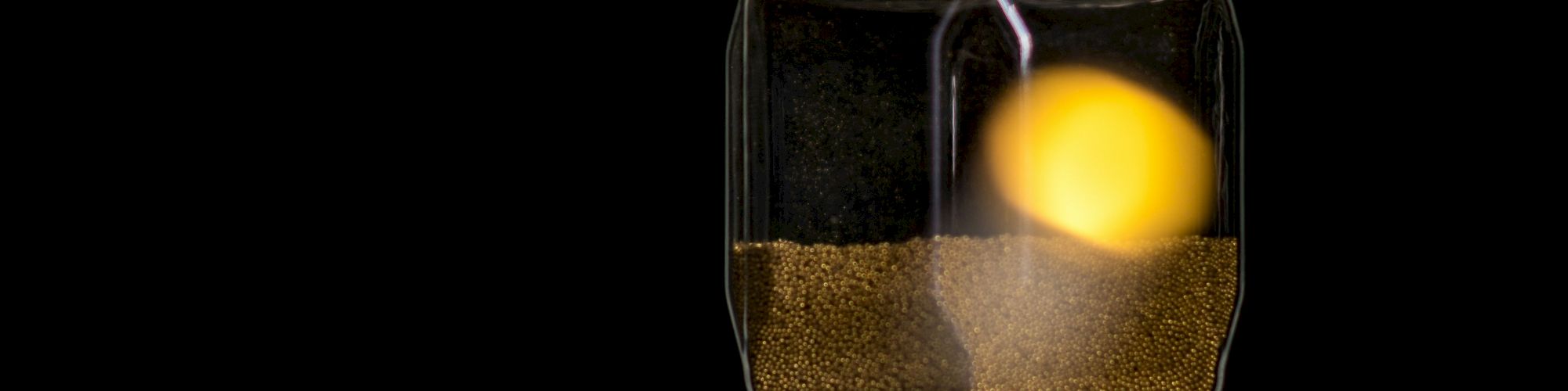 An hourglass with sand flowing, set against a dark background, with blurred yellow lights creating a whimsical effect in the background.