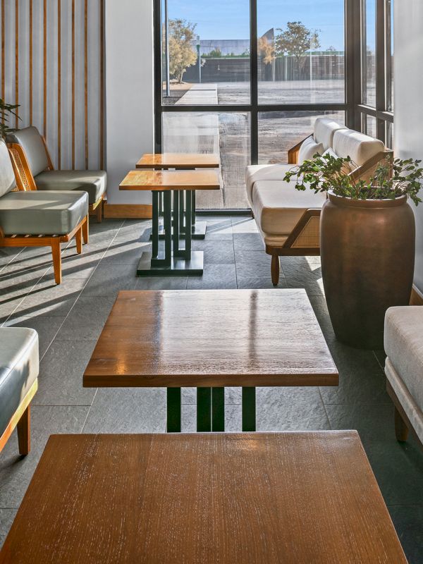 A modern lounge with comfy sofas, wooden tables, and soft natural light streaming through large windows, creating a calm, stylish vibe.